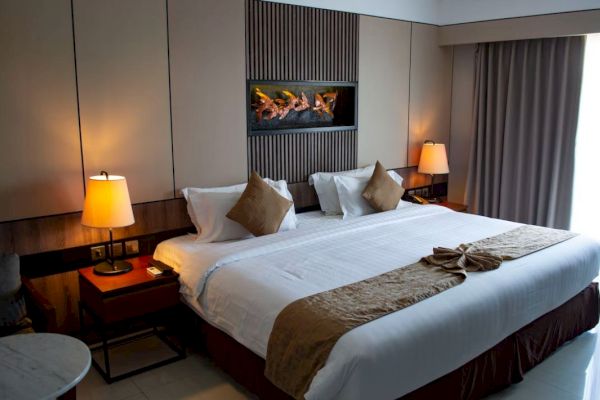 A well-decorated hotel room featuring a large bed with two pillows, bedside tables with lamps, and a contemporary wall-mounted artwork.