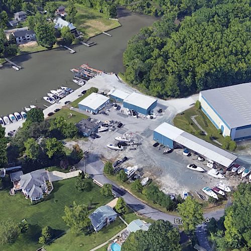 The image shows an aerial view of a marina with docks, boats, buildings, and wooded areas nearby.